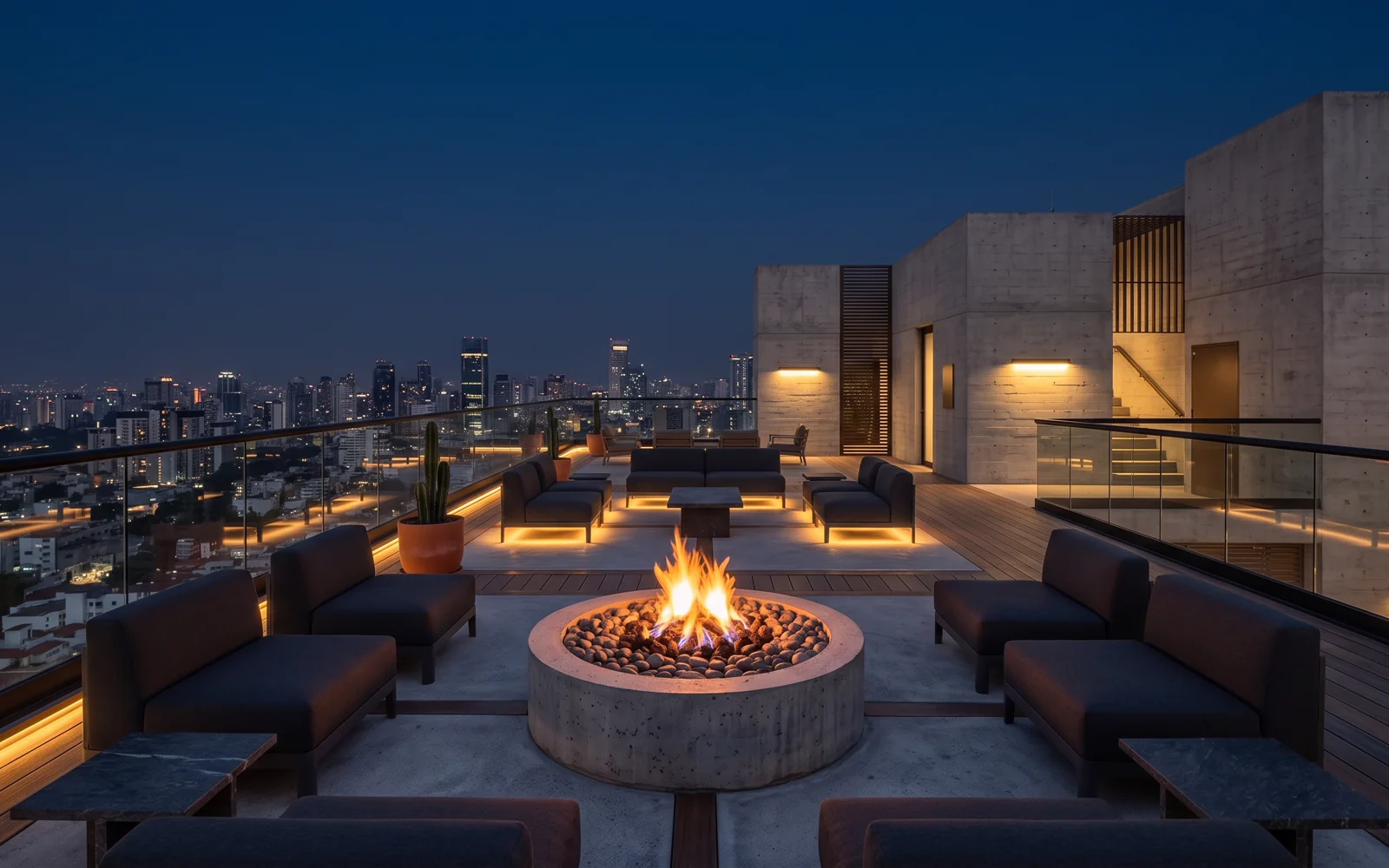 Rooftop lounge en la cima del edificio con fogatero central y vista panorámica nocturna